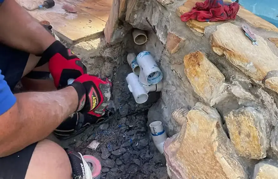 Technician inspecting a pool pipe for leaks
