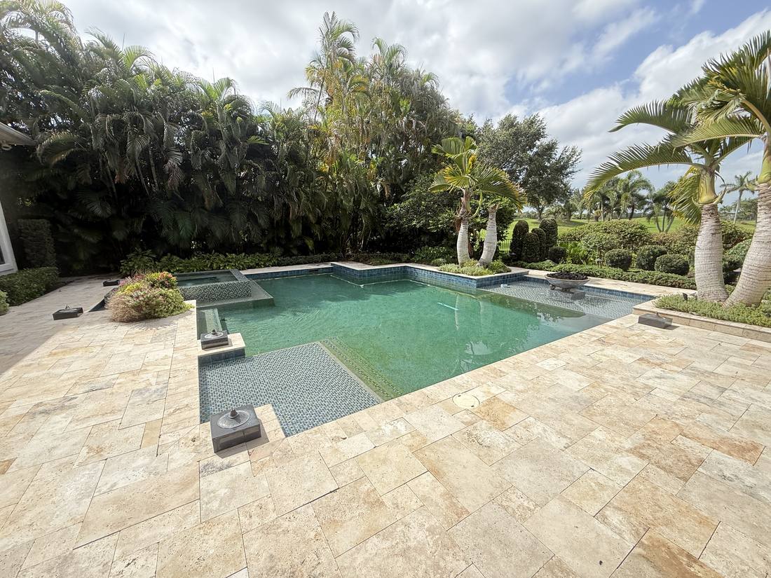 Pool and spa on a travertine deck at a Palm Beach Gardens home