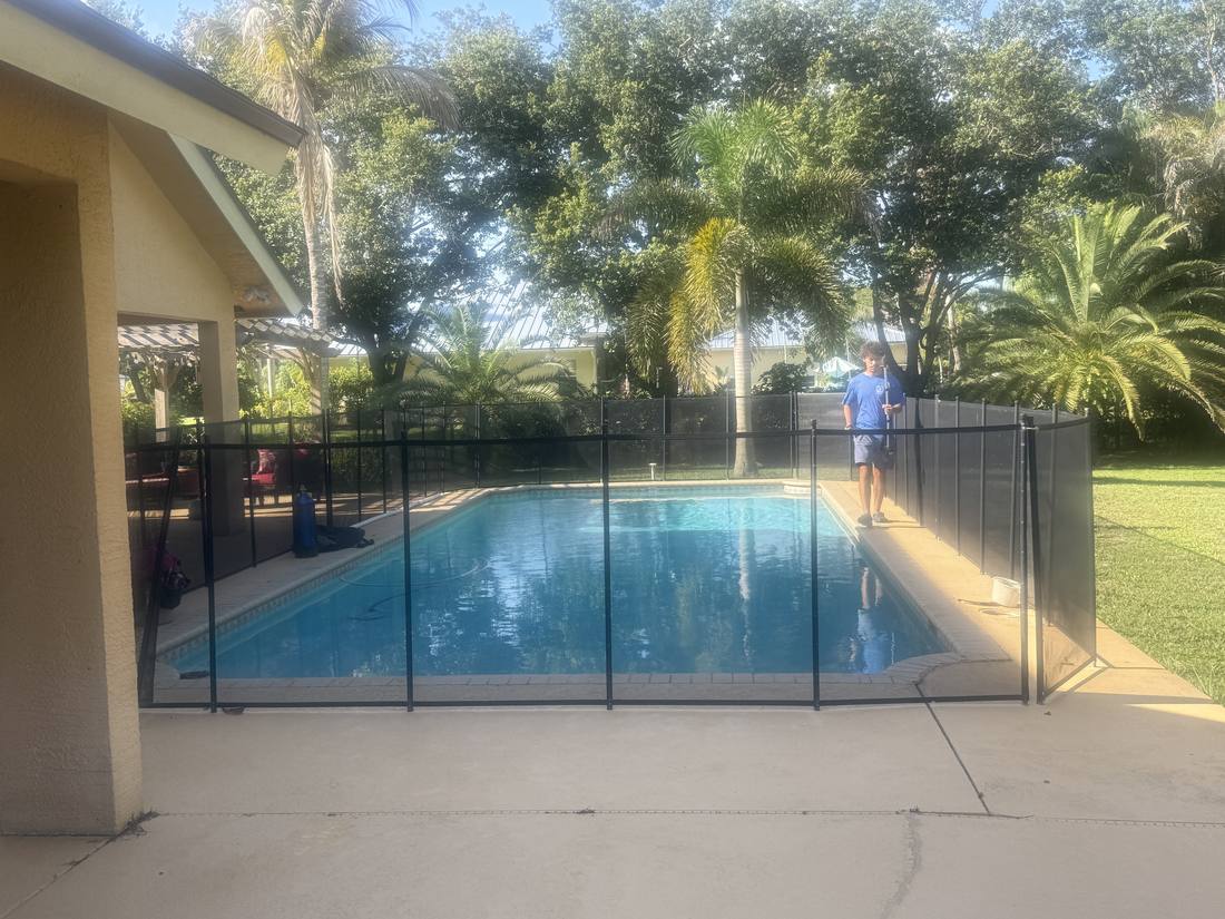 Pool with a mesh safety fence at a Palm Beach Gardens home during a leak detection visit