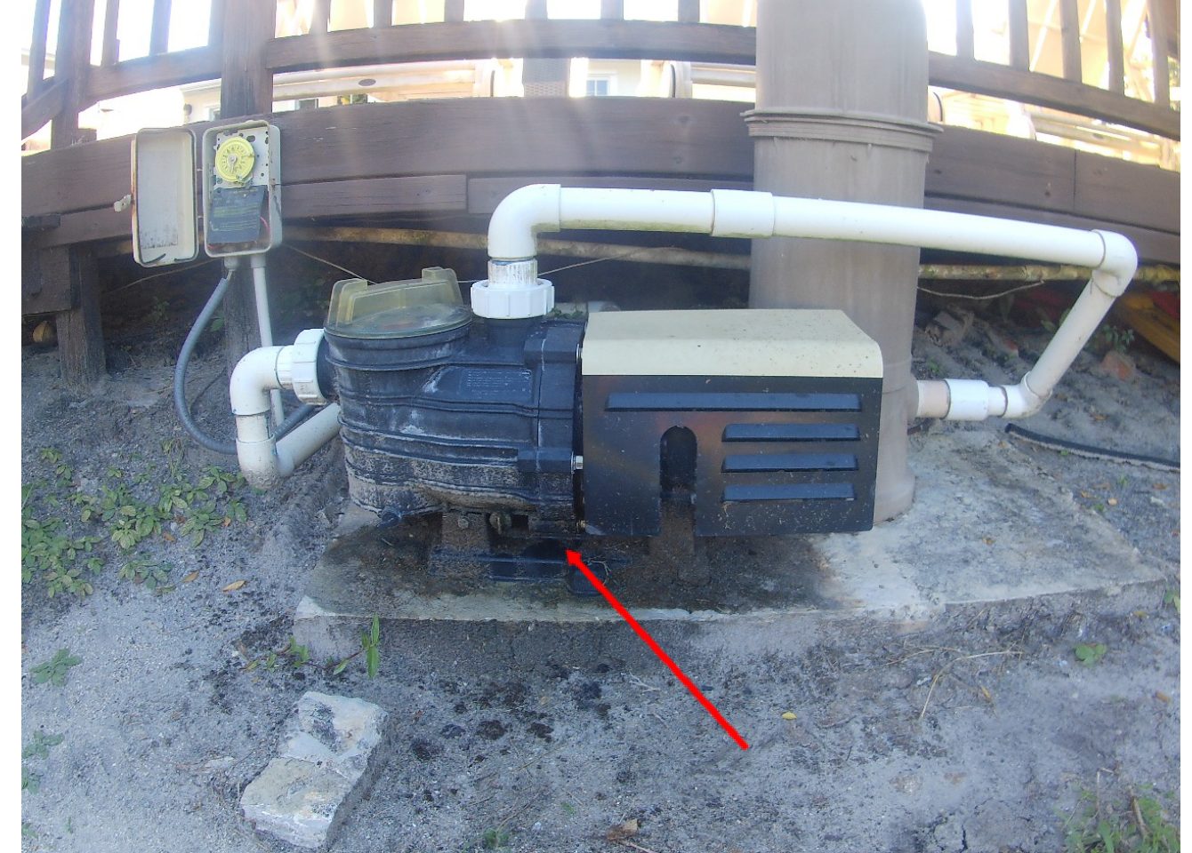 Pool pump on an equipment pad with an arrow marking active seepage at the base of the pump housing