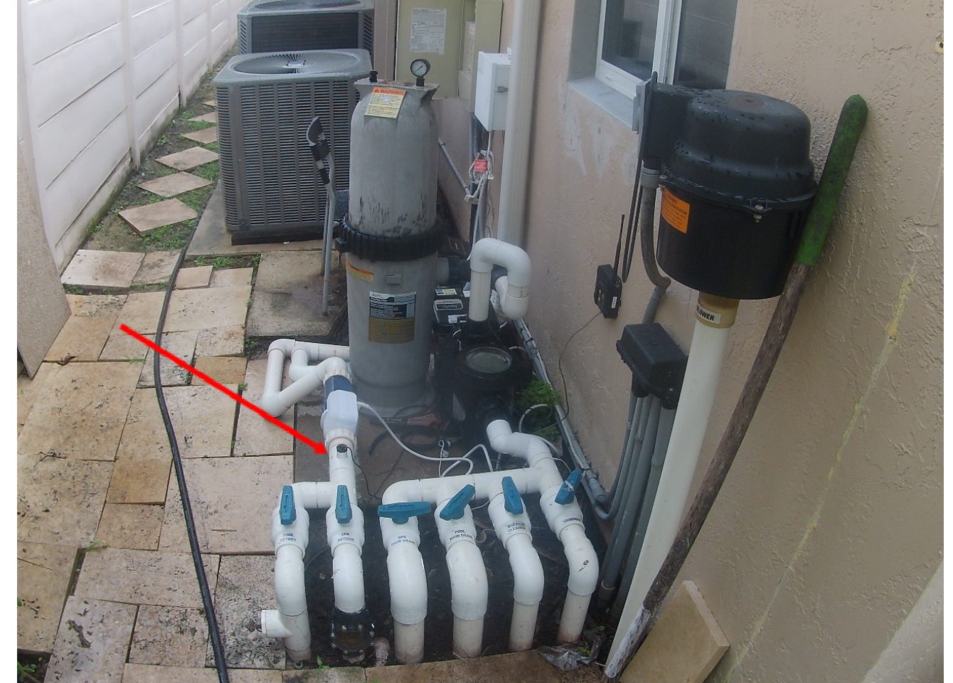 Pool equipment pad with a salt chlorine generator and an arrow marking a leak at a pipe union in the plumbing beside it