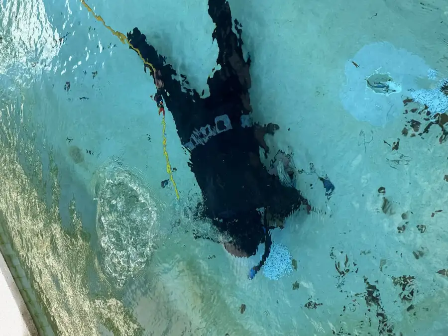 Pool technician inspecting pool underwater with equipment
